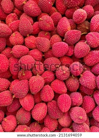 A vertical shot of a stack of pink and organic Lychee fruits