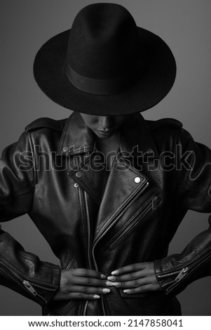 Vertical shot of styilish woman wearing hat and leather jacket. Black and white.