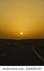 A vertical shot of sun setting over a highway with busy traffic