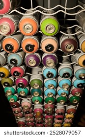 Vertical shot of tall display with stack of graffiti paints in unopened cans with dispensers in modern art and craft shop