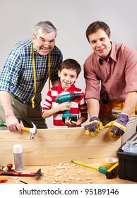 Vertical Shot Of Three Multigenerational Guys Working In A Woodshop And Smiling At Camera