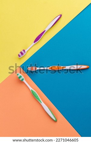 Vertical shot top view three colorful toothbrushes. Vivid multicolored background.