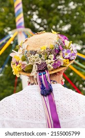 A vertical shot of a traditional English Maypole dancer with a floral hat with colorful ribbons
