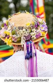 A vertical shot of a traditional English Maypole dancer with a floral hat with colorful ribbons