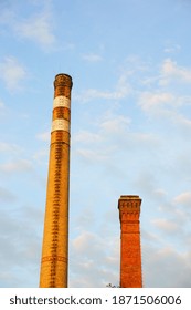 A vertical shot of two smokestacks under blue sky