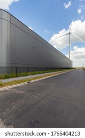 A Vertical Shot Of A Warehouse With A Windmill On The Background Under The Sunlight At Daytime