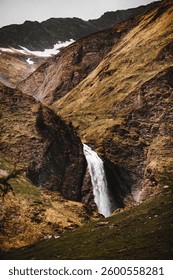A vertical shot of a waterfall flowing through mountains