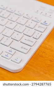 Vertical shot of white computer keyboard with selective focus on Enter key