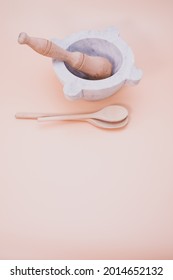 A vertical shot of wooden spoons beside mortar and pestle isolated on a pink background with copyscape