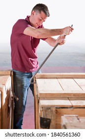 Vertical Shot Of A Worker Opening The Lid Of A Wooden Crate Using A Crowbar In A Warehouse.