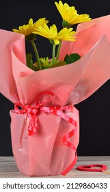 Vertical Shot, Yellow Flowering Plant Of The Aster Family, With Gift Wrap On The Table.