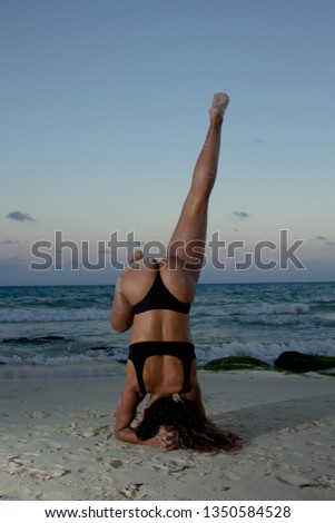 Vertical shot of young athletic woman practicing yoga on the beach, taken at Playa del Carmen, México.