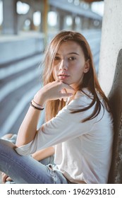 A Vertical Shot Of A Young Caucasian Female Sitting Outdoors