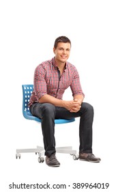 Vertical Shot Of A Young Cheerful Man Sitting On A Blue Chair Isolated On White Background