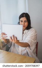 A Vertical Shot Of A Young Spanish Girl Using A Tablet Indoors