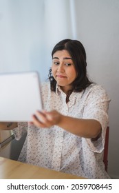 A Vertical Shot Of A Young Spanish Girl Using A Tablet Indoors