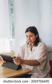 A Vertical Shot Of A Young Spanish Woman Using A Tablet Indoors