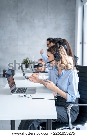 Vertical side view of beautiful blond hair call canter agent working with group of operators in office