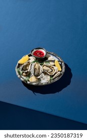 Vertical side view of fresh oysters on ice, served with lemon and vinegar sauce, set in an elegant dining context.