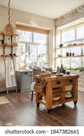 Vertical side view of stylish sunny kitchen interior with kitchenware, home decor and accessories, wooden table with homemade pastry food against cupboards and windows