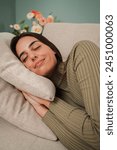 Vertical. Sleeping caucasian young woman taking nap on the sofa during the day. Exhausted female napping at living room couch having a good dream with positive expression. Paceful lady resting at home