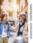Vertical. Smiling elderly couple having fun chatting standing outdoors in city. Pensioners enjoying sightseeing tour together on street in spring. Mature marriage relationship and retiree vacation.