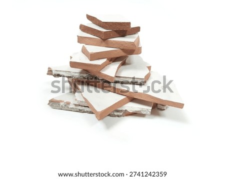 Vertical stack of broken white ceramic tiles, close up view of porcelain shards isolated on white background