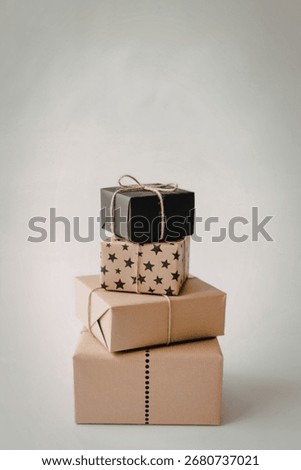 A vertical stack of four gift boxes, each wrapped in different paper and tied with twine, against a plain white background.