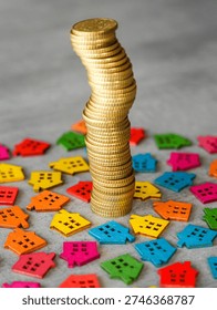 Vertical stack of gold coins surrounded by bright wooden house figures symbolizing property investment and housing market growth