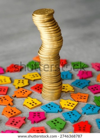 Vertical stack of gold coins surrounded by bright wooden house figures symbolizing property investment and housing market growth