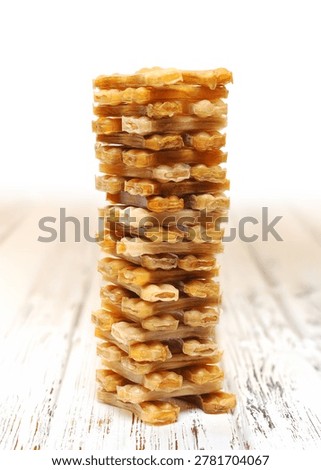 Vertical stack of rawhide dog chew treats on a rustic wooden background.