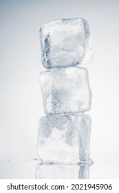 The vertical stack of three ice cubes on white background with reflection.