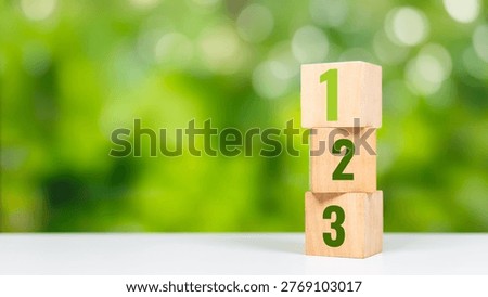 Vertical stack of wooden blocks with numbers 1, 2, 3 showing step growth or ranking. Step growth and ranking concept with stacked number blocks