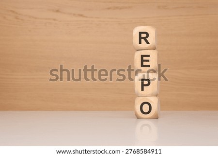 Vertical stack of wooden blocks spelling REPO on a reflective desk. Perfect concept for financial repurchase agreements, asset repossession, debt collection, or IT code repositories. Ample copy space on the left for design and text.