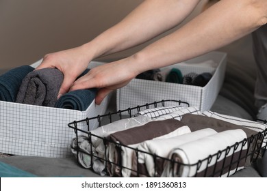 Vertical storage of clothing.Women organize clothes in a modern bedroom. Women sorting clothes in baskets room cleaning concept.