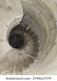 vertical structural element, likely a service shaft, utility tunnel, or spiral staircase structure found in abandoned industrial sites, bunkers, or modern infrastructure projects. 
Structure Type: It appears to be a vertical shaft, potentially a drop shaft for sewage, water management, or an access point to underground levels. 
Context: Similar structures are found in abandoned water parks, bunkers, or as part of large-scale engineering projects. 
Material: The walls appear to be made of concrete or rough rock, typical for functional underground infrastructure