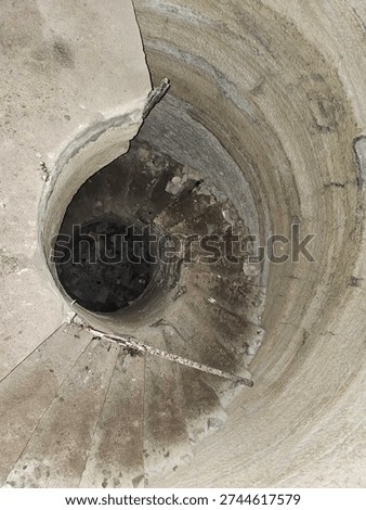 vertical structural element, likely a service shaft, utility tunnel, or spiral staircase structure found in abandoned industrial sites, bunkers, or modern infrastructure projects. 
Structure Type: It appears to be a vertical shaft, potentially a drop shaft for sewage, water management, or an access point to underground levels. 
Context: Similar structures are found in abandoned water parks, bunkers, or as part of large-scale engineering projects. 
Material: The walls appear to be made of concrete or rough rock, typical for functional underground infrastructure