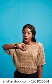 Vertical Studio Portrait Of Black Woman Getting Late For Something Checking Time, Blue Background