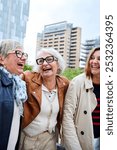 Vertical. Three cheerful only mature Caucasian friends women enjoying walking happy together in urban. Older gray hair tourists female people strolling laughing European sightseeing holidays outdoors 