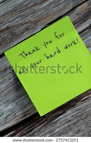 Vertical tilted image of one green sticky note that says Thank you for all your hard work, stuck on a wooden surface.
