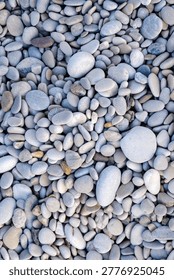 Vertical top down capture presenting an extremely solid and tightly knit natural flooring composed entirely of varied coastal pebbles.