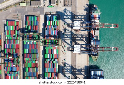 Vertical top down view of cargo containers piled on the quayside and cranes unloading the goods from ships, which are parking at the dock of Taipei Harbor, in Bali District, New Taipei City, Taiwan