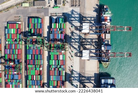 Vertical top down view of cargo containers piled on the quayside and cranes unloading the goods from ships, which are parking at the dock of Taipei Harbor, in Bali District, New Taipei City, Taiwan