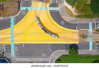 Vertical top down view of a metro train of Danhai Light Rail Transit turning at the intersection of two streets, in Tamsui District, New Taipei City, Taiwan - Powered by Shutterstock