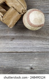 Vertical top view angle of old baseball and weathered leather mitt on rustic wood. Plenty of copy space. 