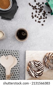 A Vertical Top View Of Chocolate Cream Donuts On A Messy Kitchen Table