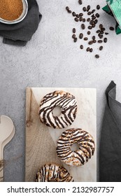 A Vertical Top View Of Chocolate Cream Donuts On A Messy Kitchen Table