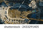 Vertical top view of construction of circular building. Stock footage. Construction site of building near parking lot in city center. Construction of stadium in center of residential city on sunny