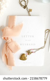 A vertical top view of a letter to my husband card and a heart locket for a groom on their wedding day