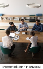 Vertical top view multi-ethnic businesspeople sitting at desk gathered in modern board room discussing planning solve common problems. Concept of teamwork, partnership and brainstorm image from above - Shutterstock ID 1480126883